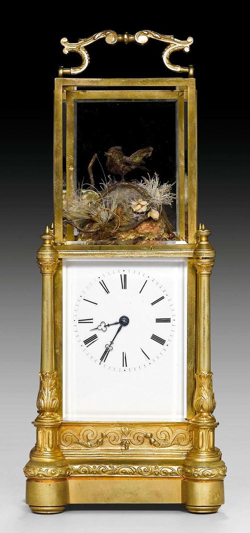 SMALL TABLE CLOCK WITH BIRD AUTOMATON,late Restauration, probably Geneva, 19th century. Gilt bronze, brass and cut glass. Enamel dial with 2 blued hands. Glazed upper section with small moving bird with real feathers and song, surrounded by branches and grasses, triggered on the hour and on demand. 12x10x26.5 cm.