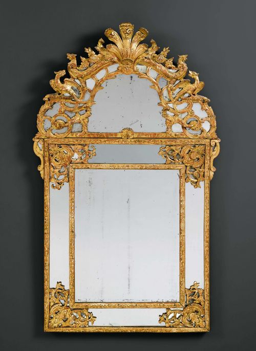 IMPORTANT MIRROR "AUX GRIFFONS", Regence, Paris ca. 1720. Wood, pierced and opulently carved with griffins, mythological creatures, cartouches, flowers, leaves and decorative frieze, and gilt. Some losses. H 163 cm. W 95 cm. Provenance: - from a private collection, Suisse romande.