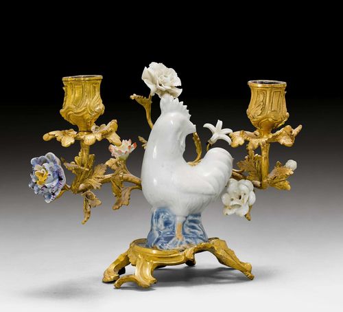 SMALL CANDELABRA WITH PORCELAIN FIGURE, Louis XV, the porcelain is from China, probably 18th century, the flowers are from France, 19th century, the bronze from Paris, 18th century. Porcelain and gilt bronze. Rooster standing in front of 2 flowering branchlets with vase-shaped nozzles and colourful porcelain blossoms, probably associated. H 16.5 cm. W 21.5 cm. Provenance: - from the estate of M. Iseli-Mooser, Suisse romande.