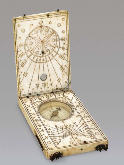 AN IVORY DIPTYCH SUNDIAL, Nuremberg, circa 1640. Sign. IK (Jacob Karner circa 1612-1648). Ivory with red, green and black engravings, brass hook. Base (inner face) with compass and marked "3" surrounded by hour scale 4-12-8 and dials for the Italian resp. Babylonian hours. The inner face of the cover with horizontal scale 6-12-6, string gnomon lost. The outer face with lunar disk on 4 brass feet. The cover engraved with wind rose and directions and graduated 1-32. The inner face with lunar disc. Closed 9x5.7x1.5 cm.