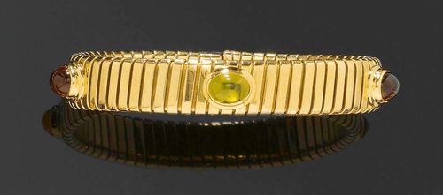 CITRINE, PERIDOT AND GOLD ARM CLASP, BULGARI. Yellow gold 750, 57g. Classic "Tubogas" arm clasp, decorated with 2 appliqued citrine cabochons totalling ca. 2.50 ct and 1 peridot cabochon of ca. 1.50 ct in a prong setting. Ca. 6 x 5 cm. Signed. With original case.