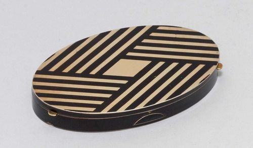 SMALL POWDER COMPACT,marked, probably 20th century. With maker's mark. Oval compact with geometric pattern in gold and black. The inside with a mirror, two powder compartments, and a removable holder for lipstick. L ca. 9.5 cm.