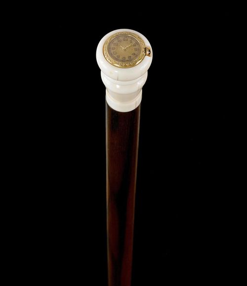 WALKING STICK WITH WATCH,ca. 1900. Ivory grip with inlaid watch, dial with Arabic numerals and gold-coloured hands. Makassar ebony stick with horn tip. L 94 cm.