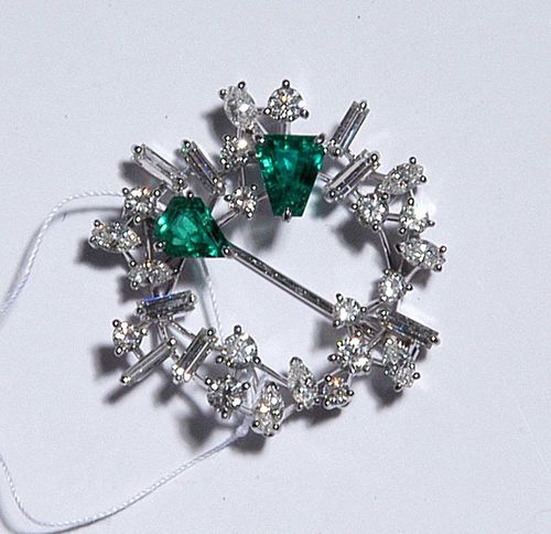 DIAMOND AND EMERALD BROOCH, E. MEISTER. White gold 750. Very elegant brooch in the form of a floral wreath, decorated with 2 emeralds totalling ca. 1.35 ct, fantasy cut as well as 13 brilliant-cut diamonds totalling ca. 1.06 ct, 8 baguette-cut diamonds and 8 navette-cut diamonds totalling ca. 1.66 ct.