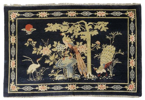 A BLUE GROUND BAOTOU CARPET DECORATED WITH A PAIR OF PEACOCKS IN A GARDEN. China, around 1900, 204x135 cm.