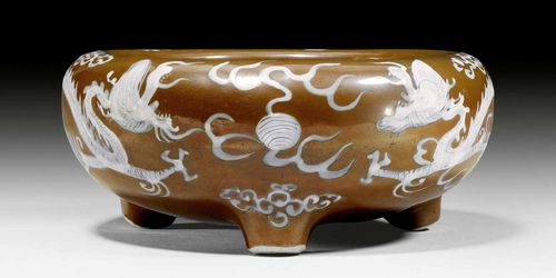 A BROWN GLAZED TRIPOD CENSER DECORATED WITH TWO WHITE DRAGONS. China, late Ming dynasty, diameter 21.5 cm.