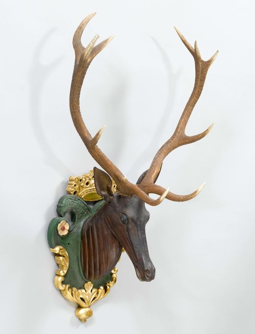 DEER HEAD WITH ANTLERS, 19th century. Wood, carved and painted green/gold. Base with crown and double-eagle. 70 x 107 cm.