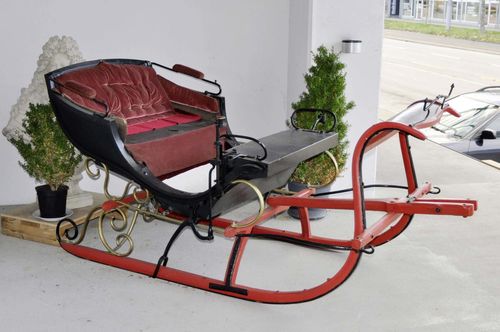 HORSE-DRAWN SLEIGH, probably Germany, 19th century. Wood painted red and black, reinforced with cast iron bands. Rectangular open body on 2 wooden rails. 2x2 seats arranged one behind the other, storage compartment with hinged cover under the second row. 220x115x109 cm.