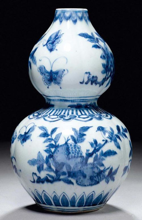 DOUBLE GOURD VASE.China, Qing-dynasty, H 25 cm. Underglaze blue decoration of birds and butterflies. Minor chip on lip.