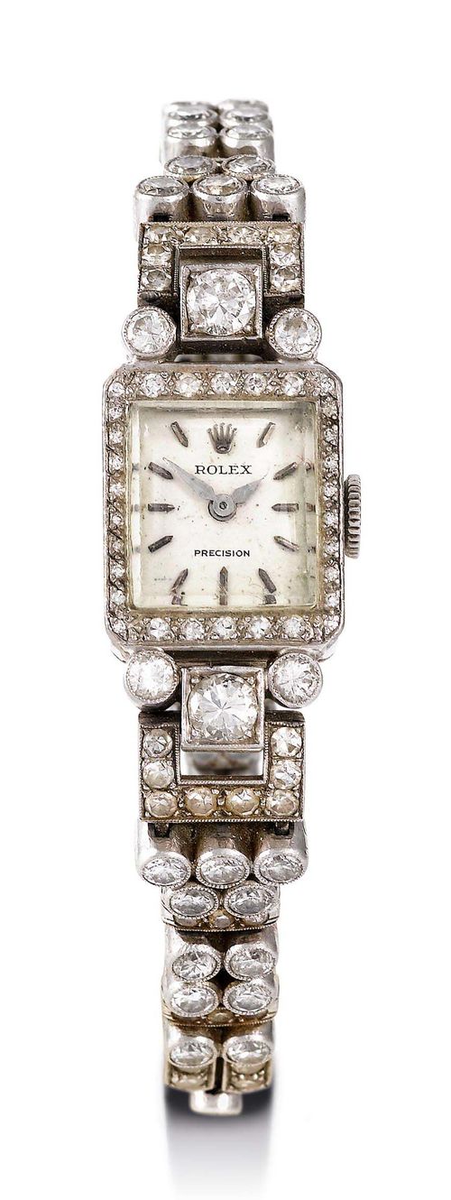 ROLEX LADY'S WRISTWATCH, ca. 1950. White gold 750. Rectangular case No. 1522 with diamond lunette. Lugs and band links set with diamonds (1 is missing). Total diamond weight ca. 2 ct. Ladder clasp stamped CB (for Bucherer), safety chain. Silver-coloured dial with applied, rhodium-plated indices and hands, signed: Rolex Precision. Small form movement with 17 rubies and shock protection, signed: Rolex Precision.